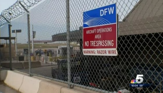 A jet taxis on the tarmac behind a security gate at Dallas Fort-Worth Airport