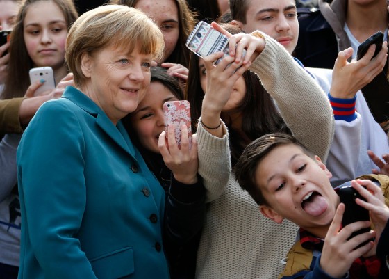 Image: Students take mobile phone 'selfies' with German Chancellor Angela Merkel as she arrives for visit at Robert-Jungk Europe high school in Berlin