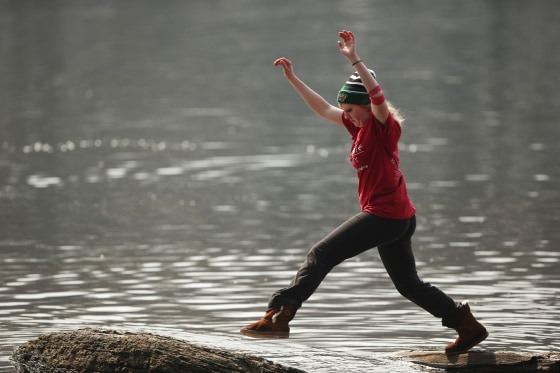 Kayla Chase leapt from one stone to another further out in the water along the banks of the Mississippi River in Minneapolis on Sunday, March 30, 2014. (AP Photo/The Star Tribune, Jeff Wheeler)