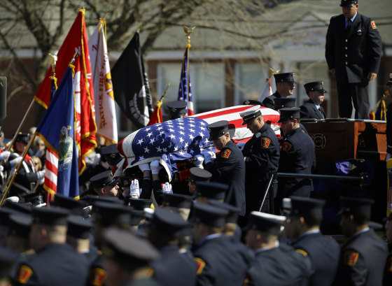 Image: The casket containing the body of firefighter Michael R. Kennedy is lowered from Engine 33 before his funeral outside Holy Name Church in Boston