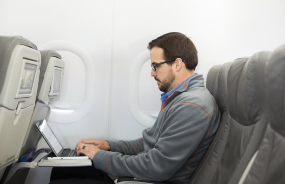 Image: A man uses his laptop on a plane