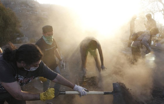 Image: Residents remove debris from their burned house after a fire burned several neighbourhoods in the hills in Valparaiso city.