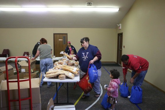 Jaime Grimes grabs a loaf of bread with her daughter Olivia, 3, and son Kevin, 13, in a food line in Lincoln, Neb.