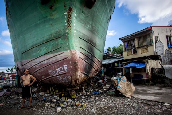 Image: A man stands in front of a large ship grounded by Typhoon Haiyan in Tacloban, Leyte, Philippines