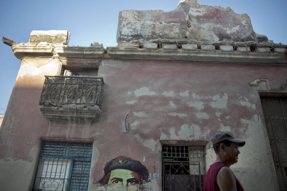 Image: A man walks past a building that collapsed due to the heavy rain next to an image of revolutionary leader Che Guevara in Havana, Cuba