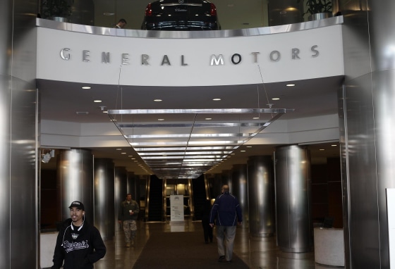 People walk near the front entrance of the General Motors headquarters April 1, 2014 in Detroit, Mich.