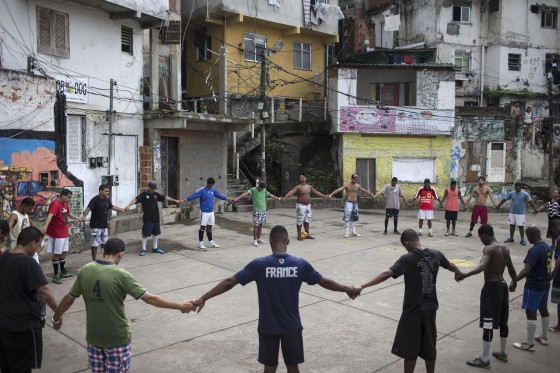 Image: Friends and neighbors of the late Douglas Rafael da Silva Pereira pray before playing soccer in the Pavao Pavaozinho slum of Rio de Janeiro