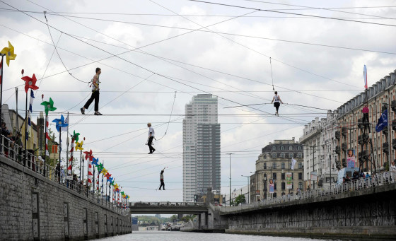 Image: Tightrope walkers perform above a canal in Brussels