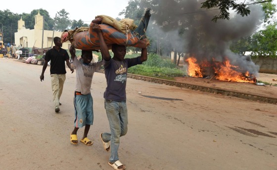 Image: Children carry furniture as they walk past a burning car outside Bangui