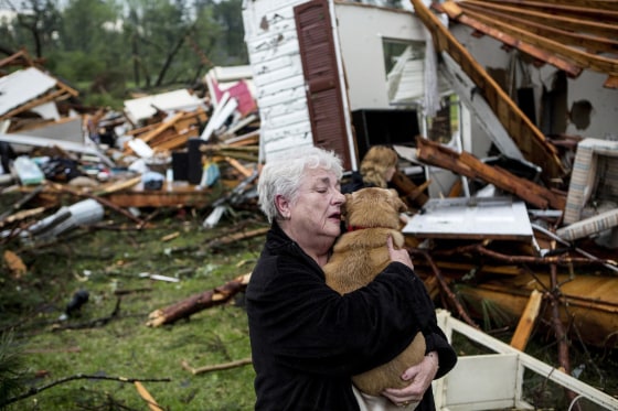 Image: Constance Lambert embraces her dog after finding it alive when returning to her destroyed home in Tupelo