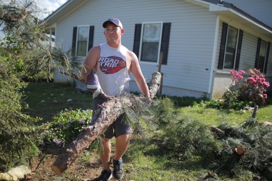 Image: Christian Gunter clears downed trees after a tornado in Vilonia, Ark.