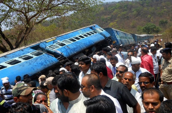 Image: People gather around a passenger train that derailed near Roha station, 70 miles south of Mumbai