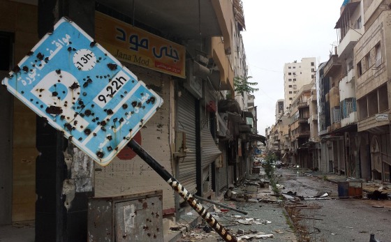 A bullet-riddled parking sign stands amid debris in a deserted street leading into the city of Homs, Syria on May 8, as rebel fighters withdrew from the city center.