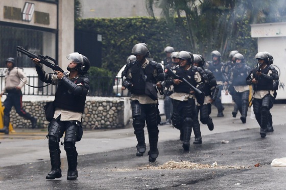 Image: National policemen advance against anti-government protesters during clashes in Los Palos Grandes