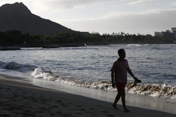 Image: A man is silhouetted as he walks along Waikiki Beach February 27, 2010 in Honolulu, Hawaii