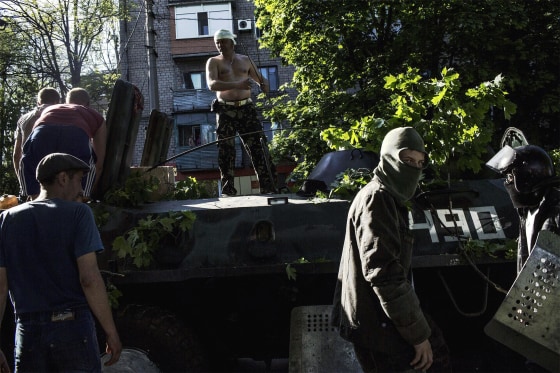 Pro-Russian activists guard a Ukrainian tank on May 10 in Mariupol, southeastern Ukraine. The tank was left by the Ukrainian army the day before due to a faulty engine as fighting between Ukrainian troops and pro-Moscow militants erupted. Witnesses in Mariupol told AFP the fighting was ferocious and involved an exchange of automatic gunfire and shelling from eight armoured vehicles. A day later after the clashes, several blocks in the centre of this normally placid port city of some 500,000 resemble a post-apocalyptic wasteland with the police completely absent and young men building makeshift barricades around gutted, blackened buildings.
