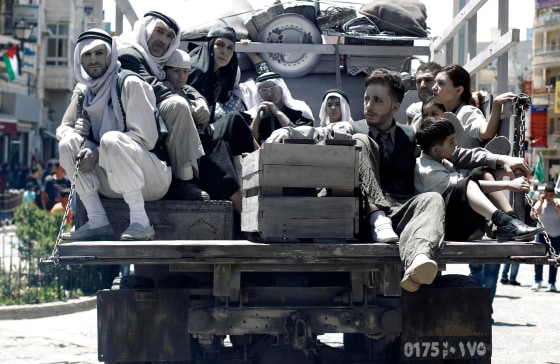 Image: Palestinians ride in a truck as they enact a symbolic scene during a rally marking the 66th anniversary of Nakba in the West Bank city of Ramallah