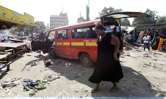 A woman walks near a damaged vehicle at the scene of twin explosions at the Gikomba open-air market for second-hand clothes in Kenya's capital Nairobi on Friday.