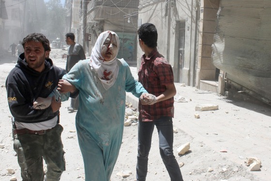 Image: Syrian residents help an injured woman following reported air strike