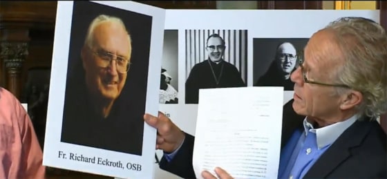 Image: A lawyer holds up a photo of Father Richard Eckroth.