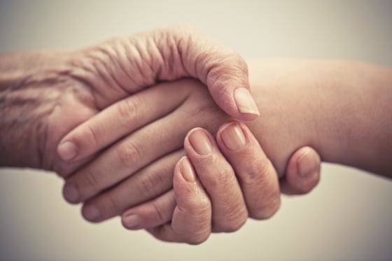 Elderly and younger person shake hands