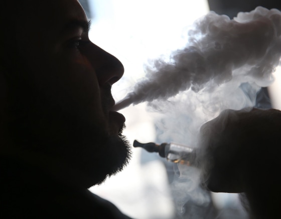 Image: Michael Crespo, a salesman, waits for customers as he enjoys an electronic cigarette in Miami
