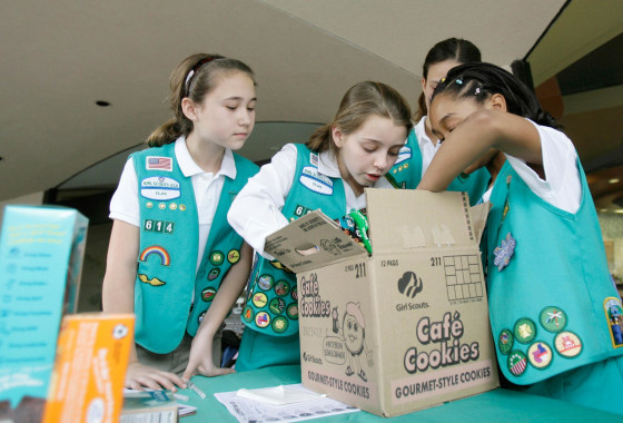 Image: Girl Scouts sort through a case of Girl Scout cookies