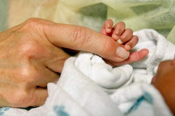 An infant grasps volunteer Kathleen Jones' hand in the neonatal intensive care unit at the University of Chicago's Comer Children's Hospital in Chicago on Wednesday, Feb. 19, 2014. Jones, 52, is one of several people who volunteer to cuddle babies at the hospital. Research shows that cuddling helps calm the babies, many who are born prematurely or who have serious health issues, and aids in their early development.
