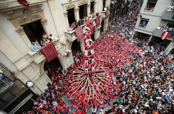 Image: Castellers Colla Joves Xiquets de Valls form a human tower called 'castells' during the Sant Joan festival at Plaza del Blat square in Valls