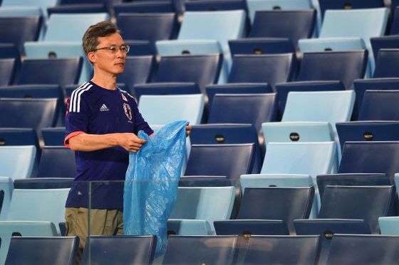 Image: A Japan fan helps collect litter from the stadium