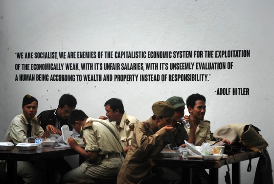 Image: Indonesian customers eat in World War II motif military uniforms at the reopened SoldatenKaffee in Bandung city, western Java island on June 21, with walls decorated with slogans from Adolf Hitle