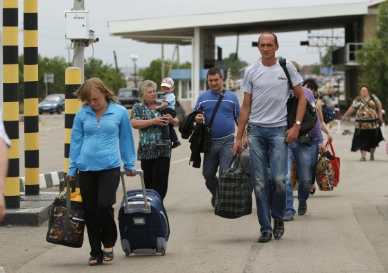 Image: People carry their belongings as they walk to cross the border into Russia at the Ukrainian-Russian border checkpoint in Izvaryne, Luhansk region, eastern Ukraine Thursday.