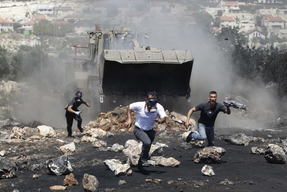 Image: Protesters run in front of an Israeli military bulldozer during clashes with Israeli troops following a protest against the nearby Jewish settlement of Qadomem, in the West Bank village of Kofr Qadom