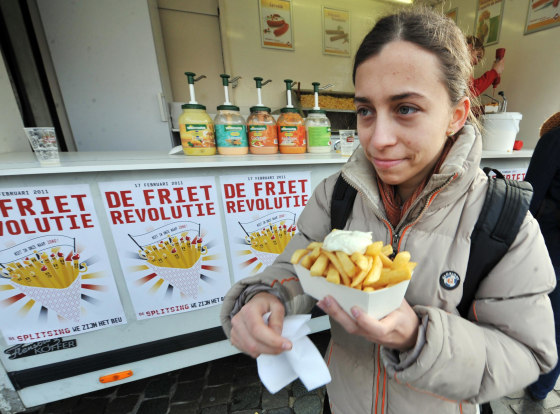 Image: A woman eats French fries (fried chips) with mayonnaise on the \"Chips Revolution\" Day\" in Leuven