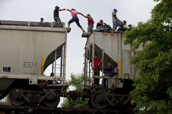 Image: A woman is helped from one boxcar to another as Central American migrants wait atop the train they were riding north, hours after it suffered a minor derailment in a remote wooded area outside Reforma de Pineda, Chiapas state, Mexico.