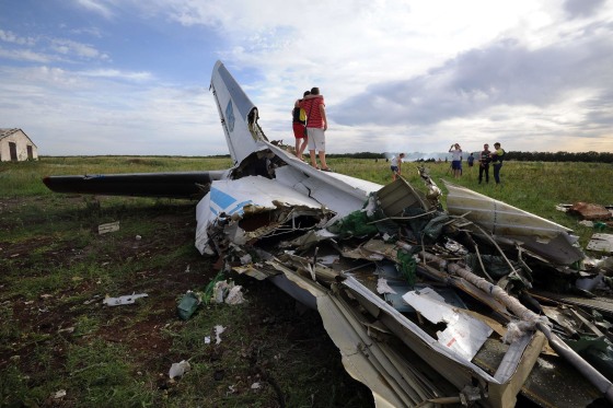 Image: People standing on the wreckage of a Ukrainian AN-26 military transport plane