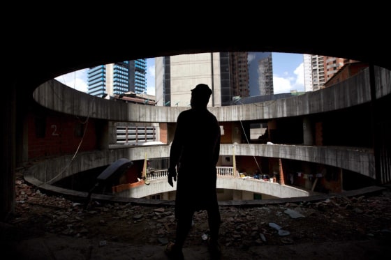 A resident waits for transportation to a new home after being evicted from the world’s tallest slum, the Tower of David, a half-built skyscraper that was abandoned in the 1990s and was transformed by squatters into a vertical ghetto, in Caracas, Venezuela, Tuesday, July 22, 2014. Officials and armed soldiers began moving out the first of thousands of squatters who have lived for nearly a decade in a soaring, half-built skyscraper in the heart of Caracas.