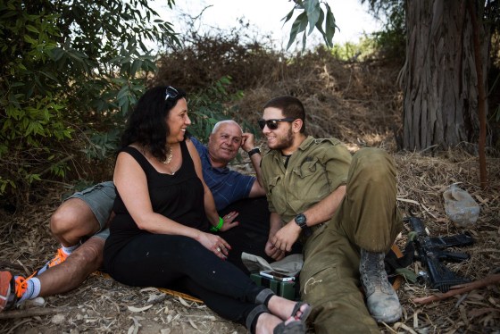 Image: Ruty Friza, left, and Pini Friza, center, meet with their son, First Lieutenant Ziv Friza during a 12-hour ceasefire just outside the militarized zone near the Israeli-Gaza border near Kafar Aza, Israel