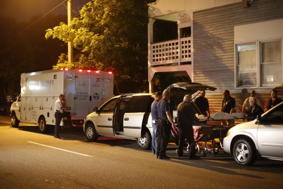 Image: A body is moved from a crime scene at an apartment complex where five members of a family, including three children, were found dead