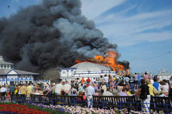Image: People look on as file engulfs the Eastbourne pier in Eastbourne, Britain