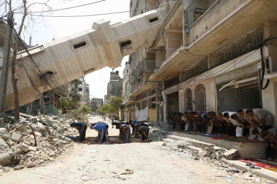 Image: Palestinians perform Friday prayers outside a mosque which witnesses said was destroyed by an Israel air strike during the offensive, on the second day of a five-day ceasefire in Gaza City