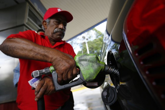 Image: A man pumps gasoline at a service station in Caracas