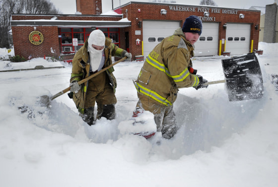 Image: Junior firefighter Adam Krach, left, and firefighter Steve Ellis of the Warehouse Point Fire Department dig snow from a hydrant outside their station in East Windsor, Conn.
