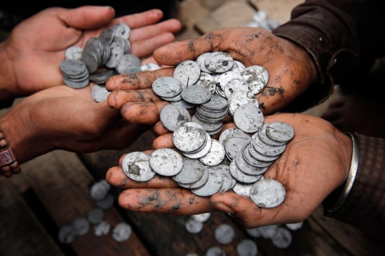 Indians sort coins offered by devotees to the river