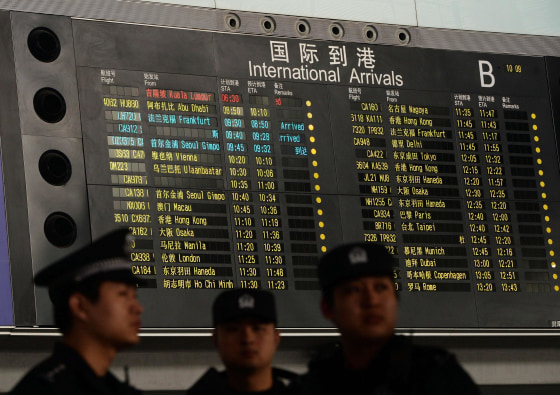 Chinese police stand beside the arrival board showing the flight MH370 (top) at the Beijing Airport after news of the Malaysia Airlines Boeing 777-200 plane disappeared on March 8, 2014. Malaysia Airlines said a flight carrying 239 people from Kuala Lumpur to Beijing went missing early on March 8, and the airline was notifying next of kin in a sign it expected the worst.