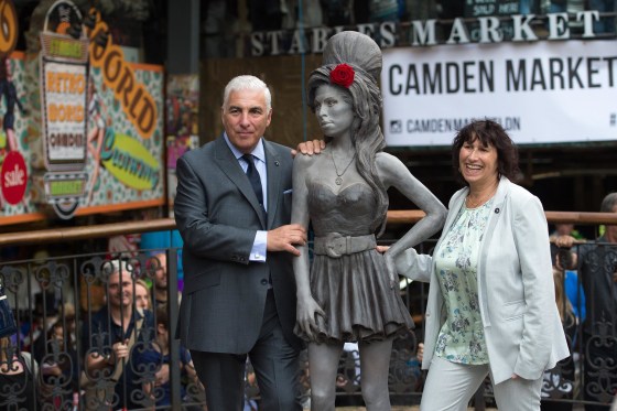 Image: Mitch Winehouse and Janis Winehouse pose for a picture with a statue of their late daughter, Amy Winehouse