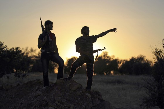 Image: Free Syrian Army fighters are silhouetted as they stand on one of the front lines of Wadi Al-Daif camp in the southern Idlib countryside