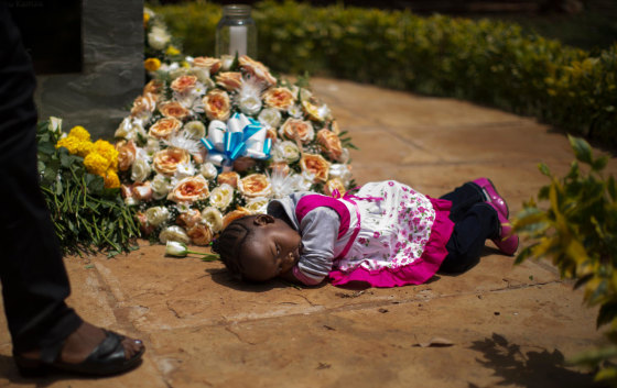 Image: Nicole Tashly, 2, lies quietly on the ground holding a white rose