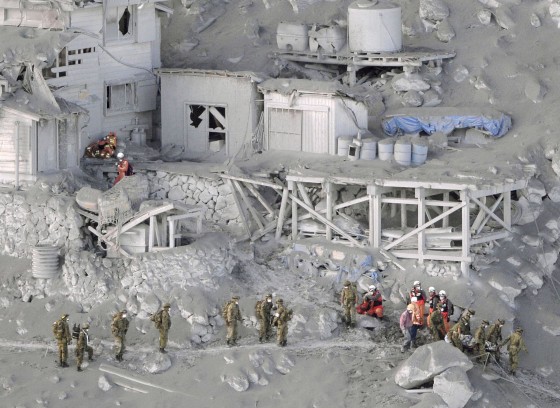Image: Firefighters and members of the Japan Self-Defense Forces carry a person rescued from a cabin