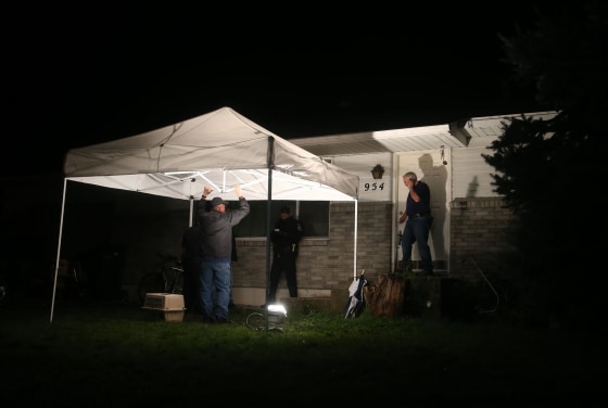 Image: Springville police officers stand outside a house where a family of five, a father, 36, a mother, 37, and children ages 14,12,11, was found dead